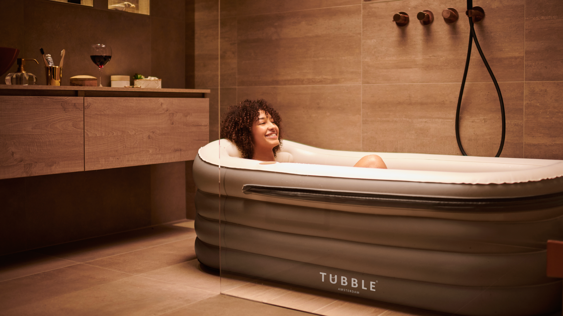 Woman relaxing in an inflatable bathtub labeled 'Tubble' in a bathroom setting.